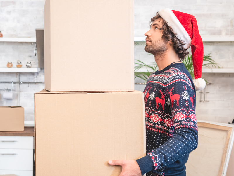 man holding moving boxes wearing festive hat